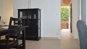 Un comedor con un armario negro, una mesa con sillas y vistas al exterior por una puerta abierta.