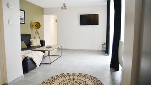 A modern living room with a sofa, coffee table, and a flat-screen TV mounted on the wall.