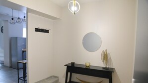 A modern interior with a black console table, a round mirror, and a hanging light fixture.