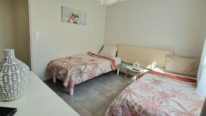 A bedroom with two beds, a bedside table, a decorative vase, and a wall-mounted picture.