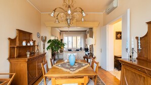 A dining room with a wooden table, chairs, a chandelier, and a large vase. - Luxury apartment next to the river (Firenze)