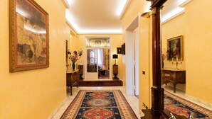 A hallway with a patterned rug, a large mirror, and a door leading to another room. - Luxury apartment next to the river (Firenze)