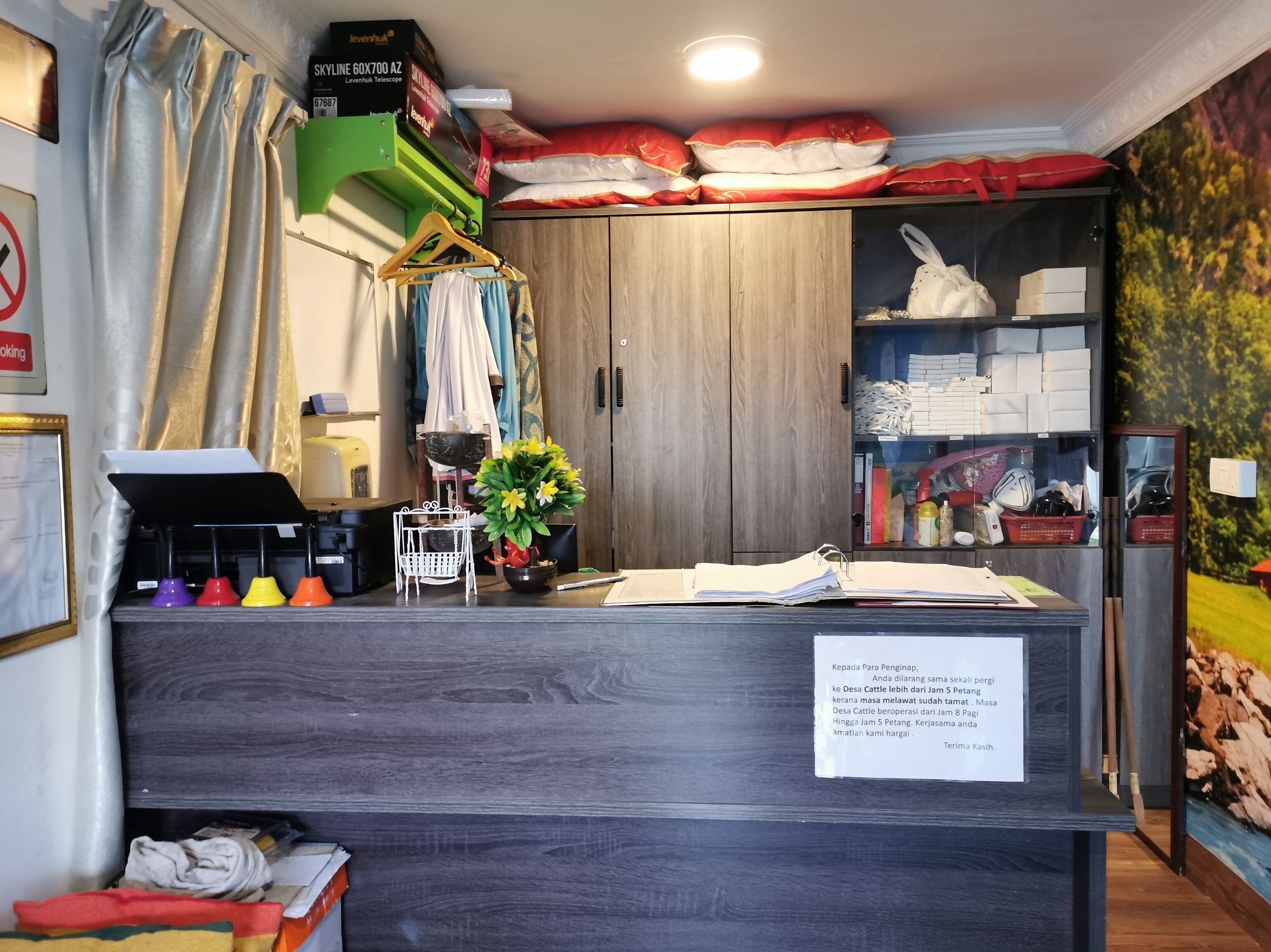 Un mostrador de recepción con un letrero, una planta y un armario de madera.