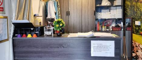 Un mostrador de recepción con un letrero, una planta y un armario de madera.