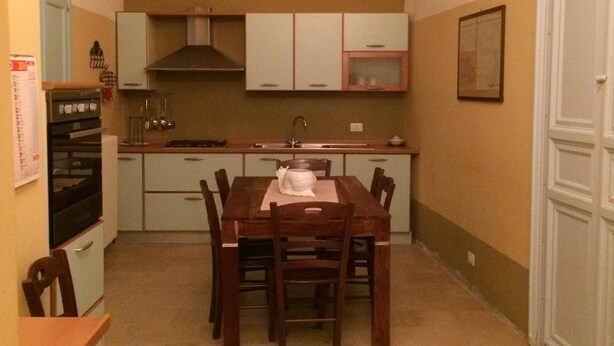 Cocina compacta con una mesa y sillas, horno empotrado y un mueble pequeño debajo de la ventana.