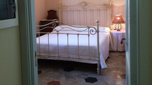 Un dormitorio con cama, mesita de noche, lámpara y una lámpara fijada a la pared.