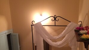 Una escalera con barandilla de metal, un paño blanco cubriendo una estructura metálica, y una estantería con flores.