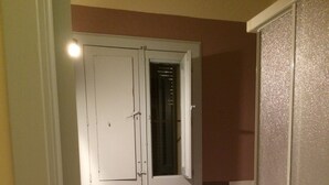 Un baño pequeño con lavamanos pedestal, inodoro y ventana con persianas cerradas.