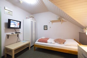 A small, cozy bedroom with a single bed, a desk, a television, and a wardrobe. - Penzion Park (Lasko)