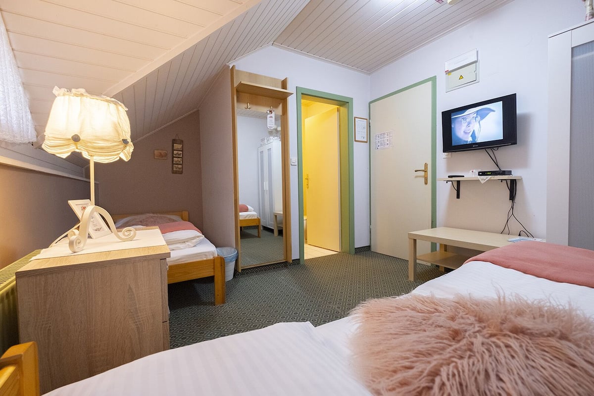 A hotel room with two beds, a desk, a television, and a mirror.