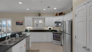 Enjoy cooking in this well-equipped kitchen with a large island, sink, microwave, oven, and refrigerator.