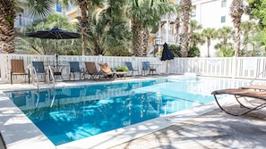 Relax by the pool surrounded by lush greenery and comfortable lounge chairs.
