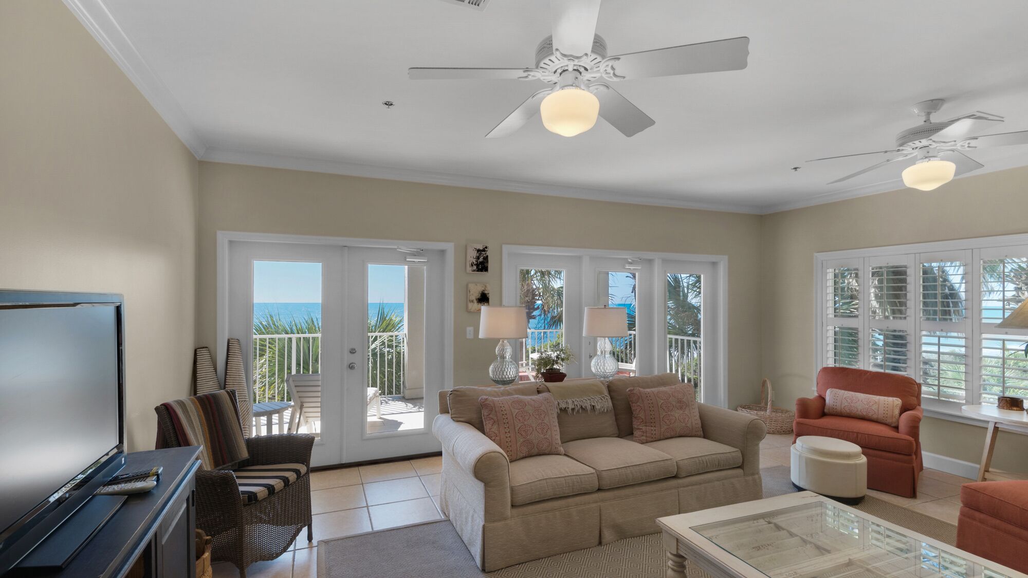 A living room with a TV, two sofas, a coffee table, and a ceiling fan.