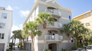Stunning multi-story building with a central entrance and arched doorways, surrounded by palm trees in a residential neighborhood.