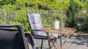 Een terras met een stoel, een tafel en een kaars.