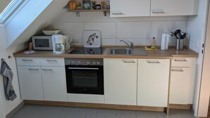 Een kleine keuken met een magnetron, koffiezetapparaat, fornuis, oven en een spoelbak.