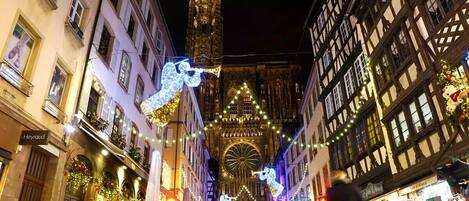 Une rue historique bordée de bâtiments richement décorés, une cathédrale imposante et des illuminations festives.