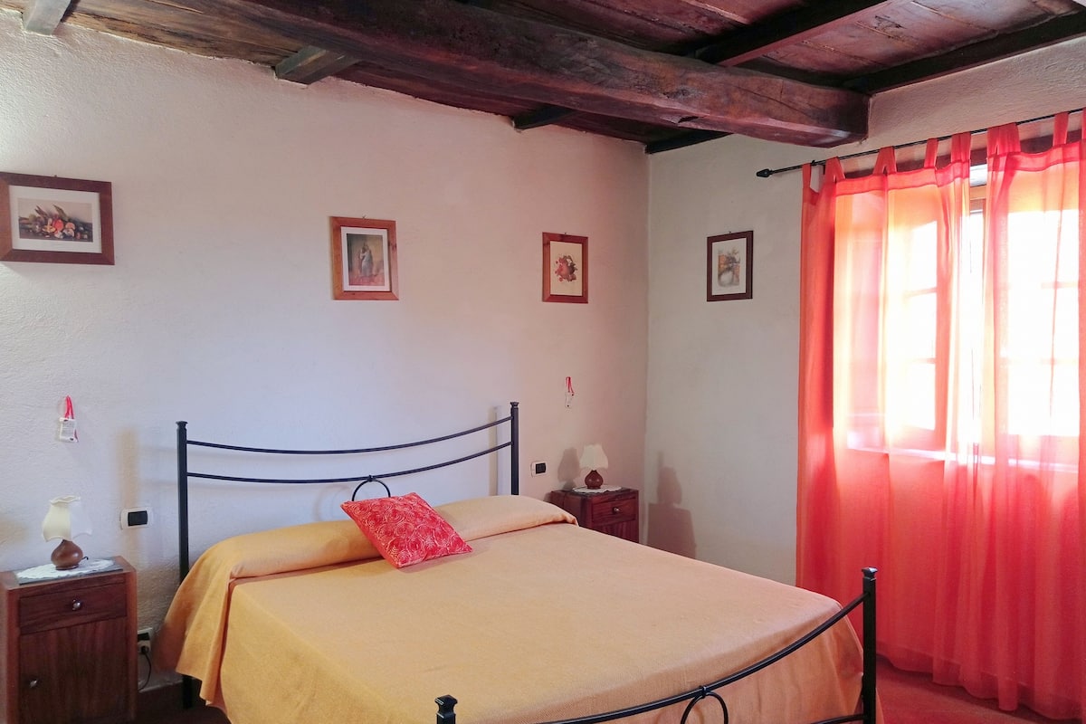 Une chambre à coucher avec un lit, une tête de lit en bois, des tables de chevet et un rideau rouge.