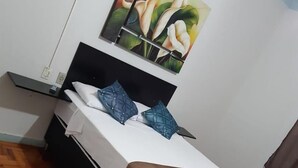 Una cama bien hecha con una cubierta marrón, un cabecero negro y dos almohadas azules.