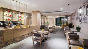 Un moderno vestíbulo de hotel con área de bar, zonas de estar y obras de arte en las paredes.