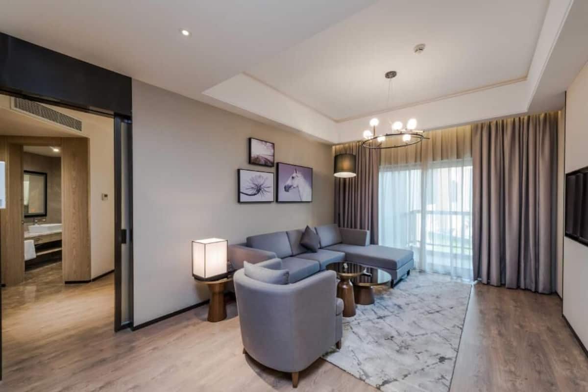A modern living room with a sectional sofa, a round coffee table, and a TV mounted on the wall.