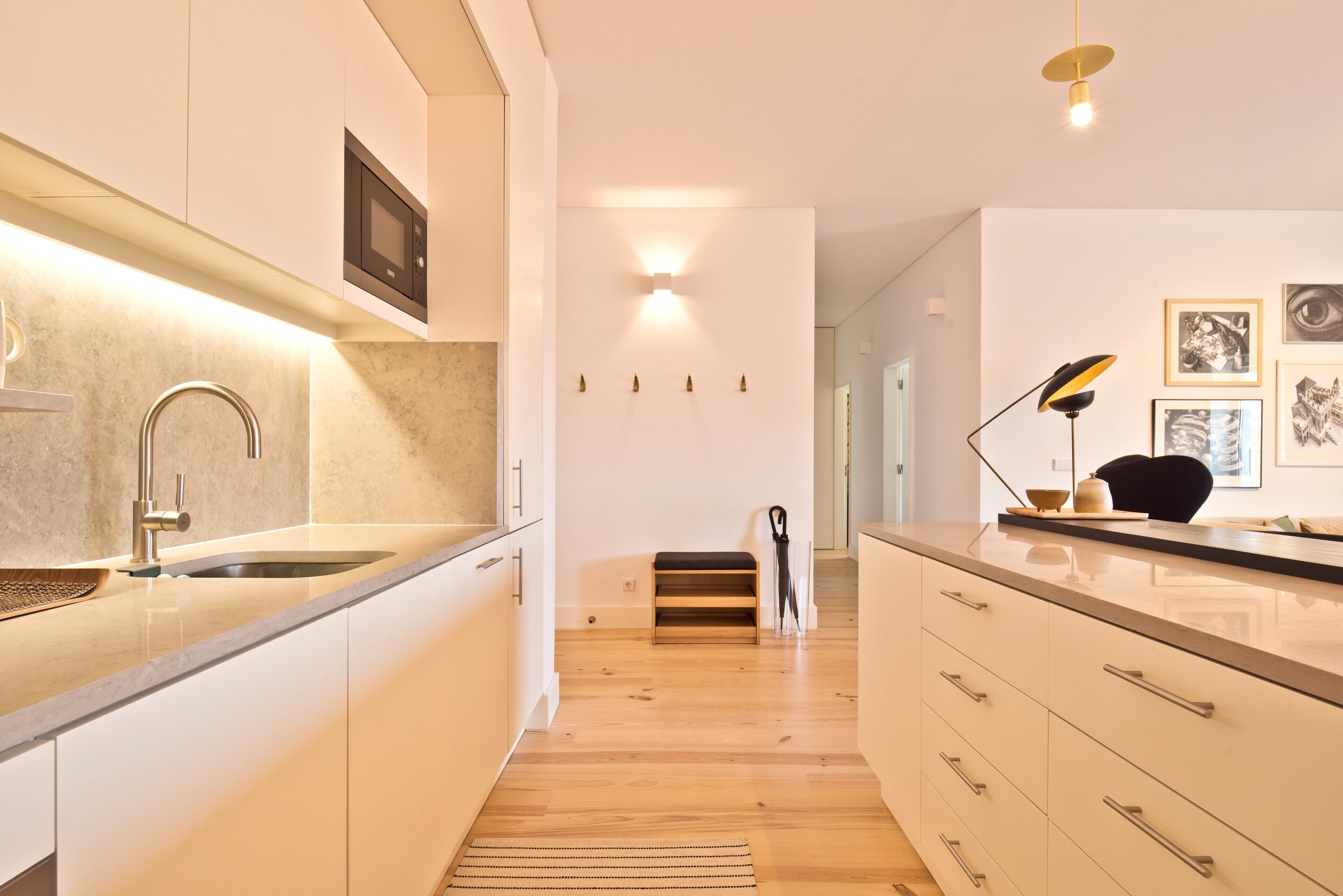 A modern kitchen with a built-in sink, wooden flooring, and a light fixture above the counter.