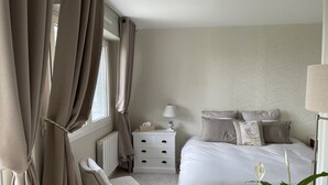 A bedroom with a bed, bedside table, lamp, chair, and a plant. - Charming 2-room terrace ideally located in a quiet area - beautiful unobstructed view. (La Baule)