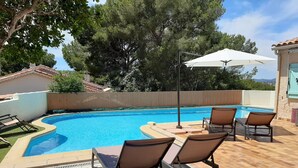 A swimming pool with lounge chairs and an umbrella, surrounded by a stone patio and trees. - Villa large pool, beach, Sanary harbor on foot (Six-Fours-les-Plages)