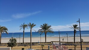 Una playa con palmeras, cielo despejado y mar tranquilo.