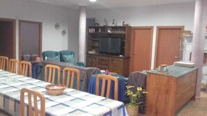 A dining area with a checkered tablecloth, wooden chairs, a television, and a cabinet with decorative items. - Villa Paraiso for Large Families (Alcanar)