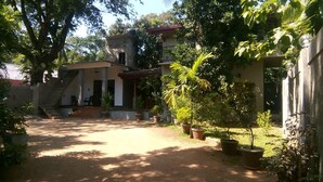A courtyard with a building, potted plants, and a staircase leading to an upper level. - Umesh Home Stay (Dambulla)