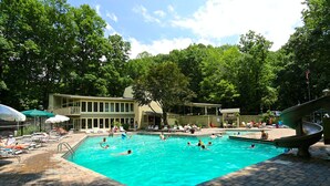 En swimmingpool omgiven av solstolar och parasoller, med en byggnad i bakgrunden.