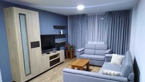 Una sala de estar moderna con un sofá gris, una mesa de centro de madera y un mueble para televisión.