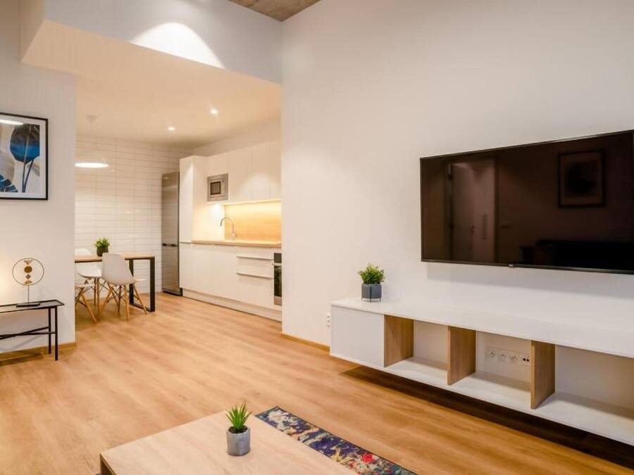 Een moderne keuken met witte kastjes, een houten aanrecht en een ingebouwde televisie.