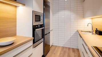 A modern kitchen with white cabinetry, a stainless steel oven, and a wooden countertop.