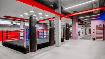 A boxing ring with heavy bags and a red and blue padded area.