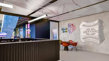 A modern gym interior with a reception desk, workout equipment, and a wall with gym branding.