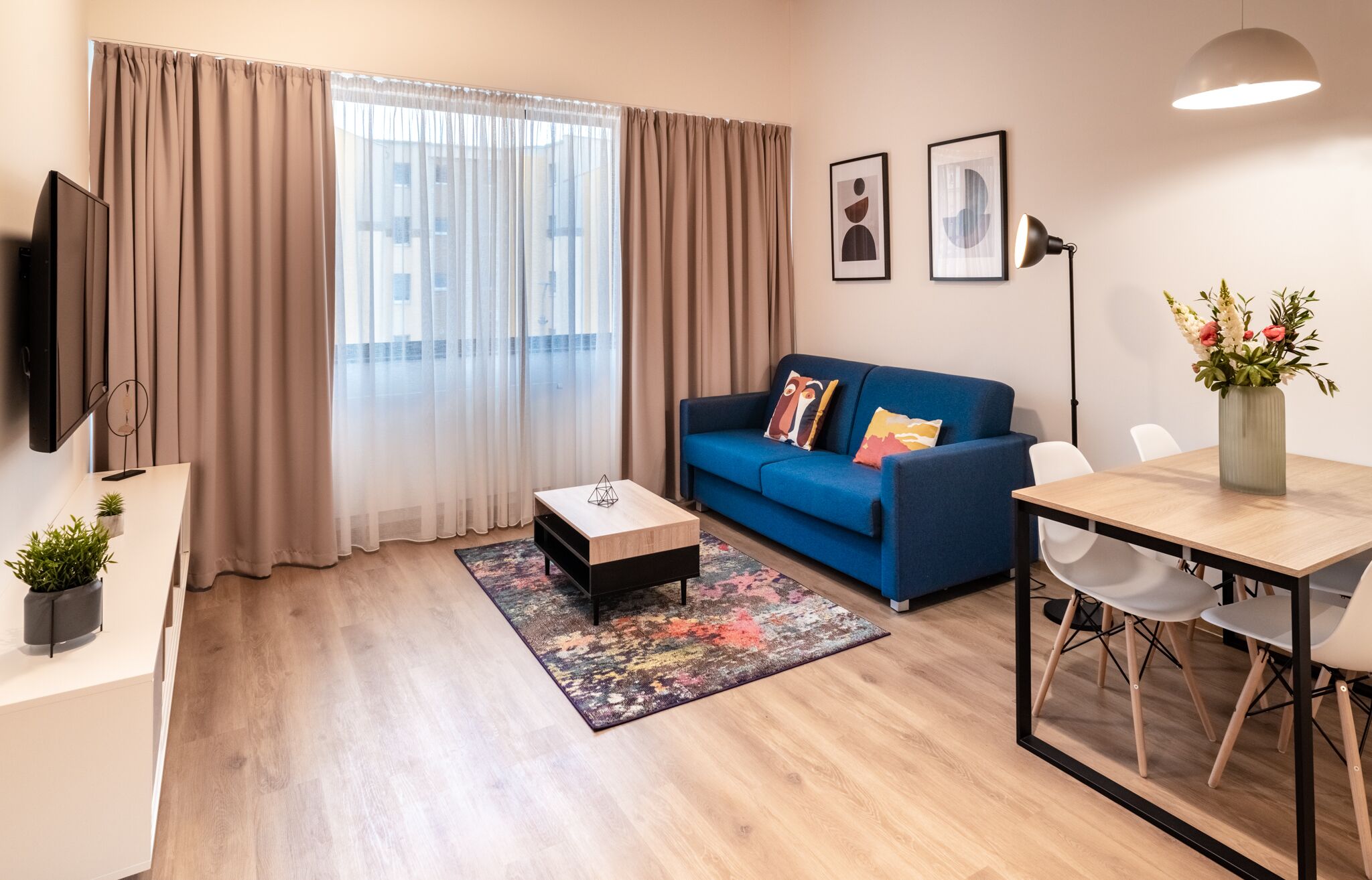 Un soggiorno moderno con un divano blu, un tavolino, una TV e un'area pranzo con sedie e tavolo.