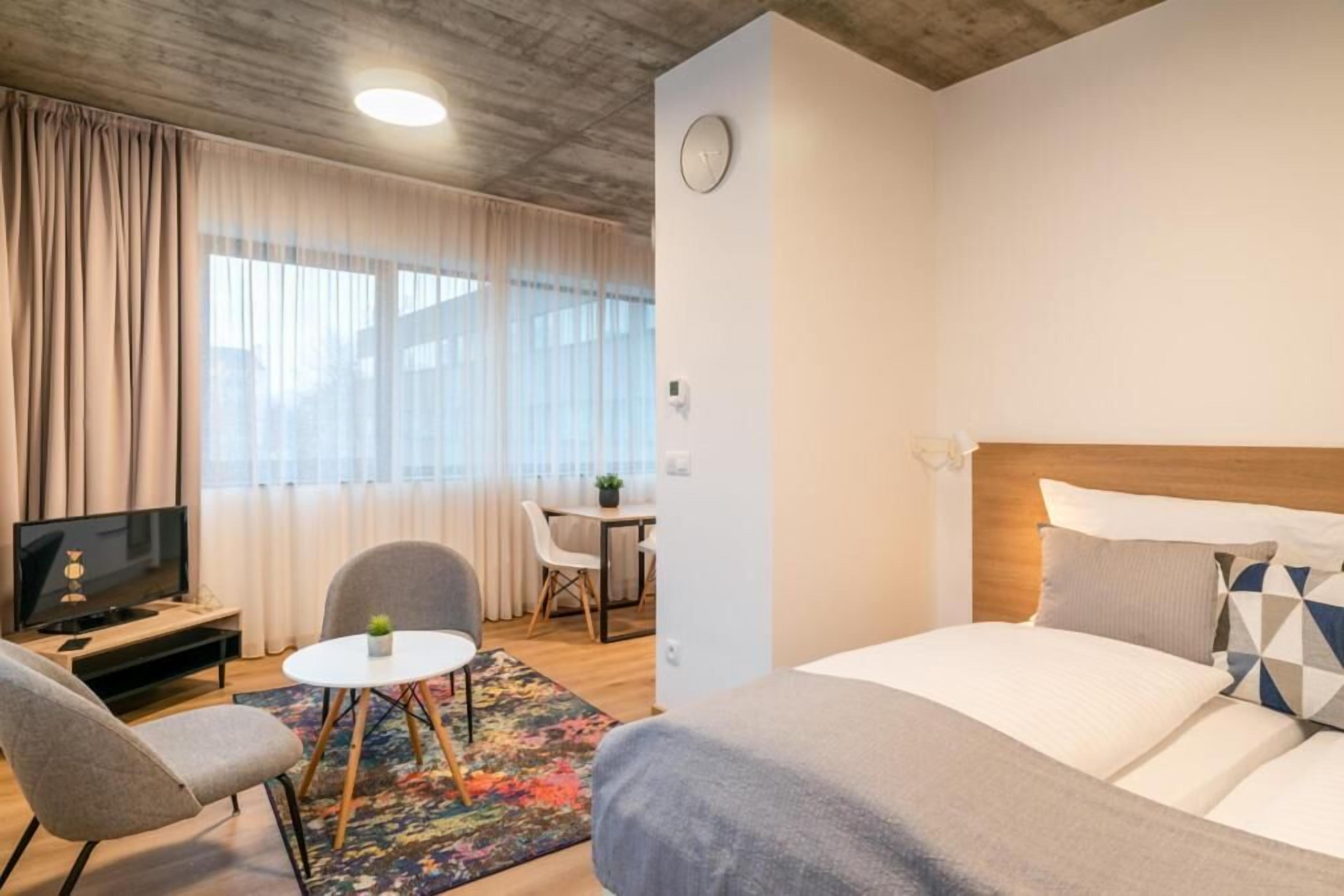 Ein Hotelzimmer mit Bett, Fernseher, Schreibtisch und Stuhl.