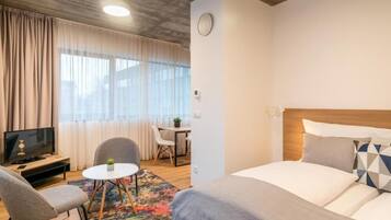 Ein Hotelzimmer mit Bett, Fernseher, Schreibtisch und Stuhl.