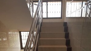 A staircase with a metal handrail, tiled walls, and windows with bars. - Kigala Hotel (Dar es Salaam)