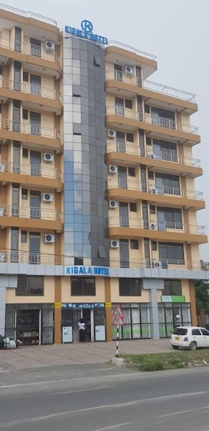 Ein mehrstöckiges Hotel mit einer zentralen Glasfassade und Balkonen auf jeder Etage.