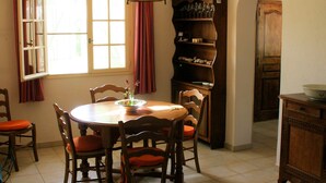 A dining area with a round table, chairs, a chandelier, a bookshelf, and a wooden cabinet. - in Bagnols-en-Forêt, quiet, with large swimming pool (Bagnols-en-Forêt)