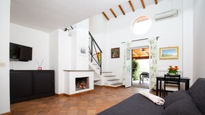 A modern living room with a fireplace, a staircase, and a dining area with a table and chairs. - Tenuta Capizucchi (Rome)