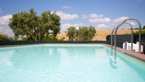 A clear swimming pool with a metal ladder and a view of trees and hills in the background. - Tenuta Capizucchi (Rome)