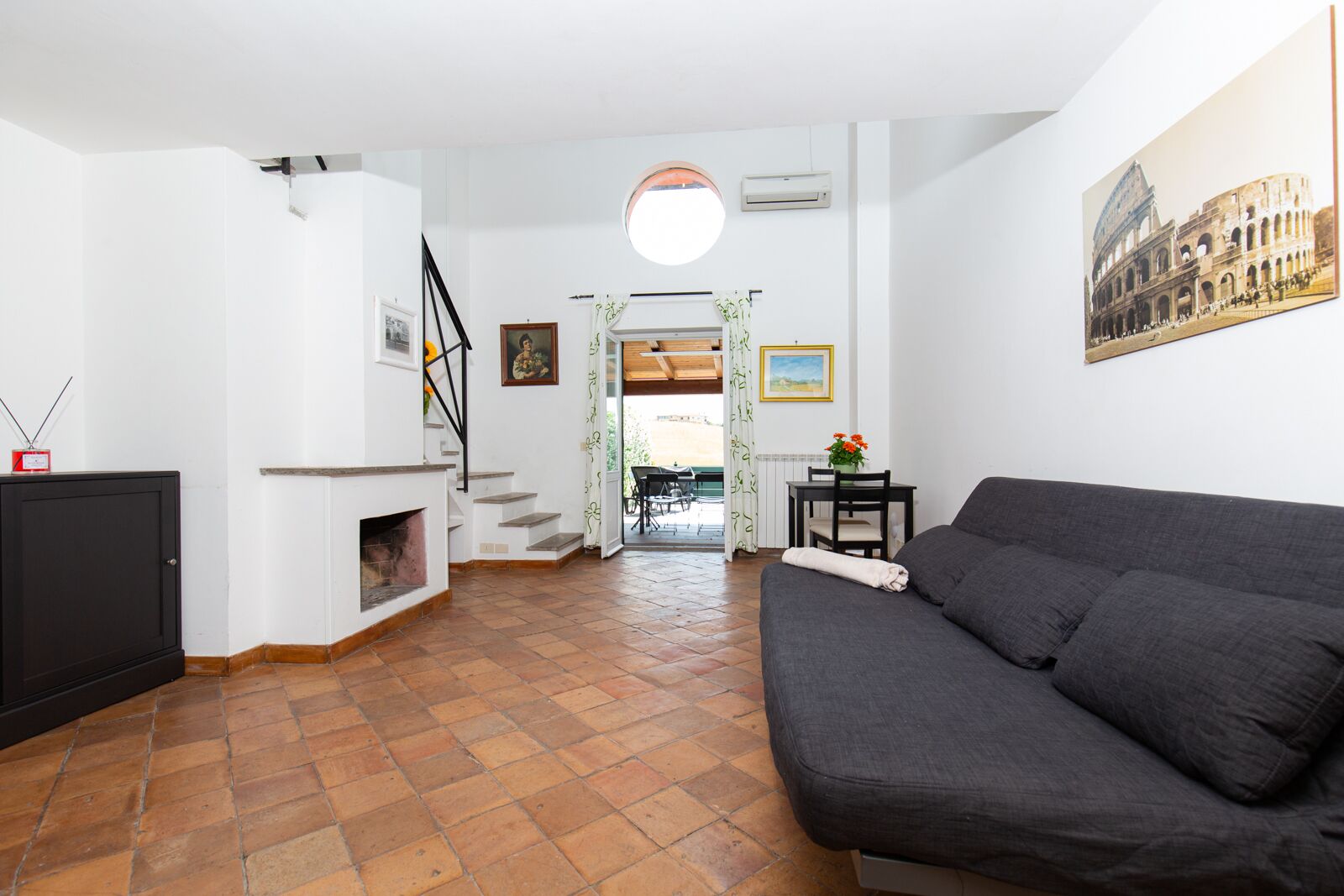 Un salon comprenant un canapé, une cheminée, un escalier et un coin repas avec une table et des chaises.