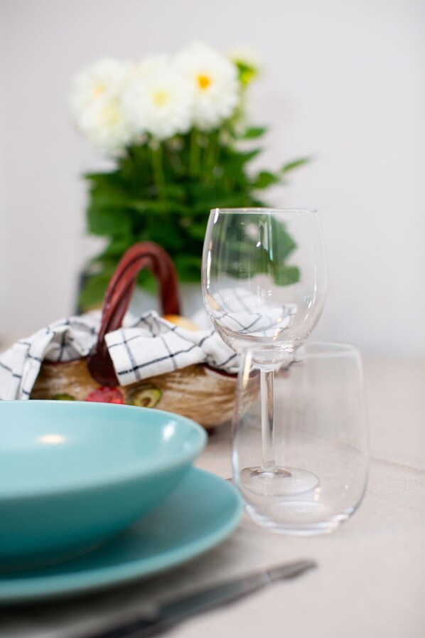 A clear glass wine glass, a blue plate, and a wicker basket with a cloth.
