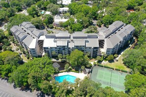 Residents enjoy a central courtyard with a swimming pool surrounded by lush greenery and other buildings.