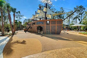 Un espace de jeux sur le thème des pirates, avec une structure en forme de navire, des toboggans et une aire de jeux.