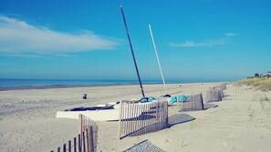 Enjoy a serene beach experience with access to the ocean and a picturesque sailboat in view.